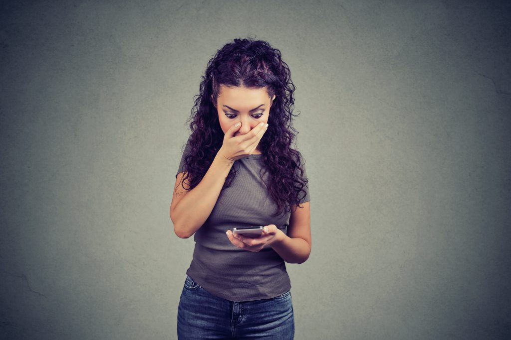 Shocked woman reading news about instagram hacking on phone